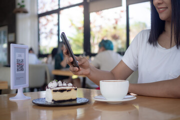 Woman use smartphone to scan QR code for order menu in cafe restaurant with a digital delivery. Choose menu and order accumulate discount. E wallet, technology, pay online, credit card, bank app..