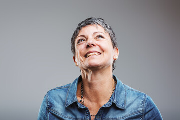 Obraz premium Smiling mature woman looking up with hope and happiness