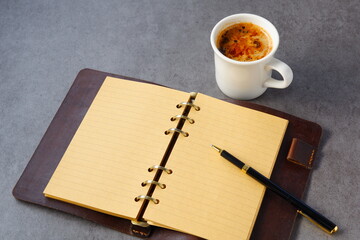 ミルクをたっぷり入れたコーヒー、カフェ・ラッテを飲みながら、システム手帳でデスクワーク中のイメージ
