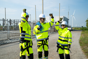 An engineer wearing safety gear closely inspects the base of a wind turbine in a renewable energy...