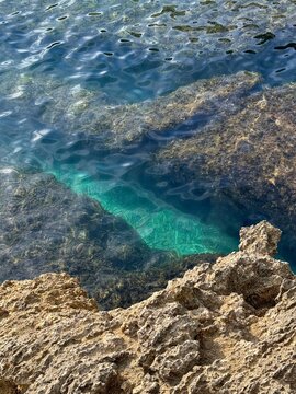 Rocky coast and turquoiuse sea water with algae.
