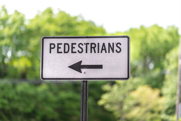 Directional Pedestrian Signpost Against a Blurred Green Foliage Background in Daylight