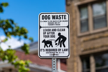 Dog Waste Removal Sign With Leash and Clean-Up Instructions in a City Park
