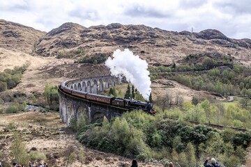 Naklejka premium Majestic Steam Train Chugging Across the Glenfinnan Viaduct, Glencore, Scotland