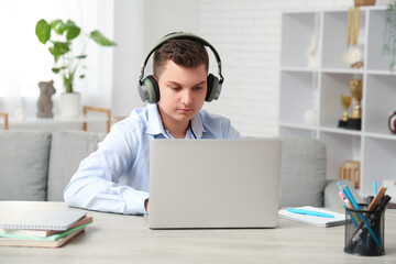 Teenage boy with laptop and headphones at home