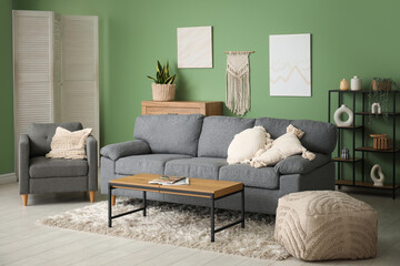 Comfortable sofa, armchair, pouf and coffee table in interior of living room