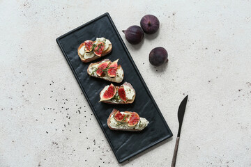 Black board of delicious fig bruschetta with ricotta cheese and rosemary on white background