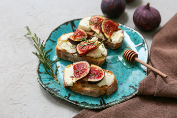 Plate of delicious fig bruschetta with ricotta cheese and rosemary on white background, closeup