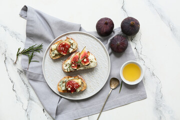 Plate of delicious fig bruschetta with ricotta and blue cheese on white background