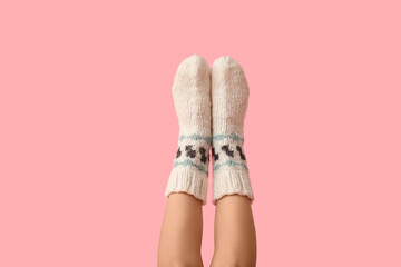 Legs of young woman in knitted socks on pink background