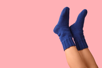 Legs of young woman in blue knitted socks on pink background