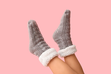 Legs of young woman in grey warm socks on pink background
