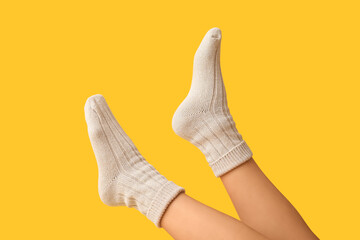 Legs of young woman in cotton socks on yellow background