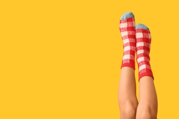 Legs of young woman in warm checkered socks on yellow background