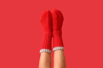 Legs of young woman in red knitted socks on color background