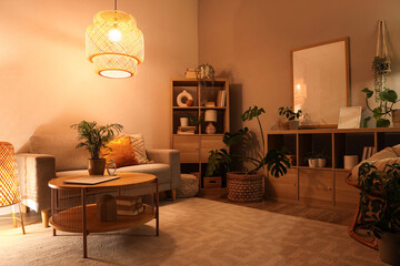 Soft sofa, coffee table and glowing lamps in interior of living room at night