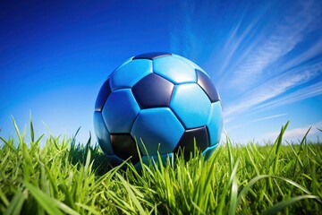 Fototapeta premium Blue and Black Soccer Ball on a Lush Green Grass Field - Perfect for Sports Photography, Soccer Camps, Outdoor Activities, and Athletic Events