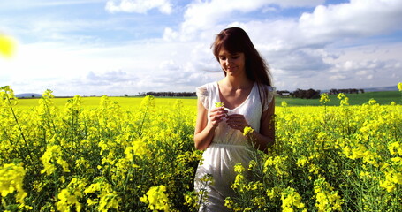 Beautiful woman walking in mustard field on a sunny day