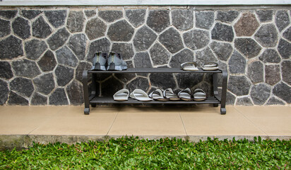 Shoe rack with different footwear near the wall. The photo is out of focus, blurred, and noisy.