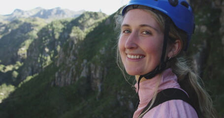 Portrait of a young happy Caucasian woman in helmet admiring the view while out zip lining on sunny