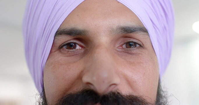 Portrait of happy biracial sikh male doctor in turban looking at camera at hospital, in slow motion