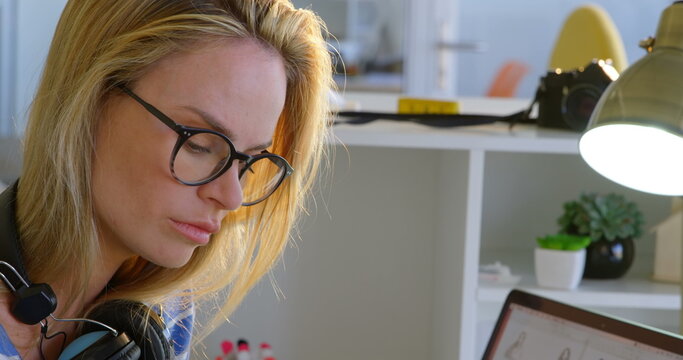 Side view of Caucasian female fashion designer using graphic tablet at desk in office