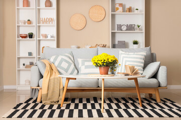 Interior of living room with sofa, book and chrysanthemum flowers on table