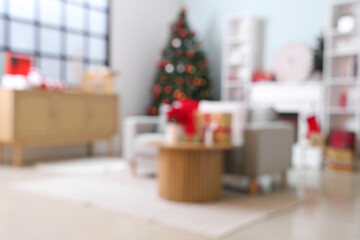 Blurred view of living room with sofa, shelf units and Christmas plant poinsettia on table