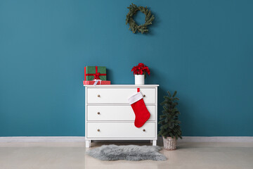 Interior of room with Christmas plant poinsettia on commode and fir tree
