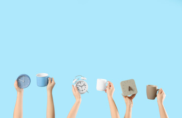 Female hands with alarm clocks and cups of coffee on blue background. Good morning concept