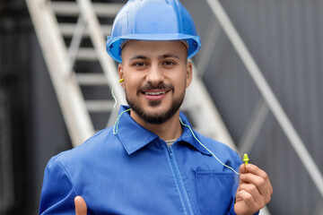 Male builder with earplugs outdoors, closeup