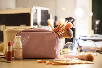 Cosmetic bag, different makeup products and accessories on dressing table in room