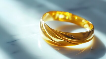 Elegant golden bangle resting on a white marble surface, illuminated by soft light, showcasing its smooth design and polished finish for a luxurious accessory look