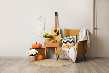 Interior of living room with chrysanthemum flowers, pumpkins and armchair