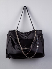 Close up of black trendy bag with silver chain  with star on white background