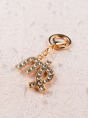 Close-up of golden keychain with rhinestones in the shape of the zodiac sign Virgo   on a light...