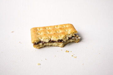 Bitten sandwich biscuit with chocolate filling on white background