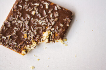 Bitten chocolate biscuit with coconut sprinkles on white background