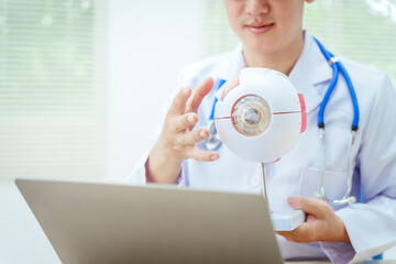 A male doctor wearing glasses sits at a desk in a hospital, explaining eye diseases like glaucoma,...