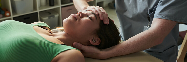 Female patient receiving treatment from professional chiropractor lying on examination table. Medical setting with healthcare professional using hands for adjustment