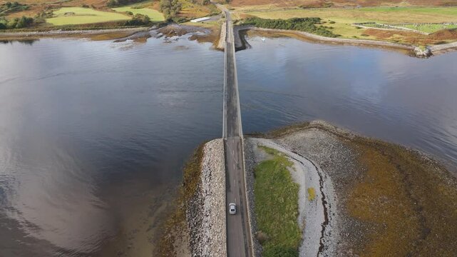 Electric car driving on Kyle of Tongue causeway bridge follow shot