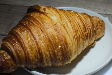 Delicious freshly baked plain croissant on plate in cafe, croissant on white plate