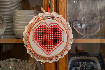 Macro abstract texture view of a framed handmade cross-stitch heart design on a white cloth