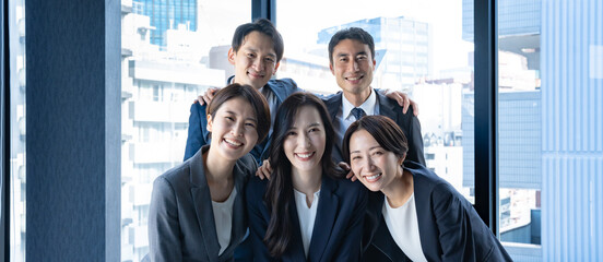 笑顔で肩を組む大勢のビジネスマン