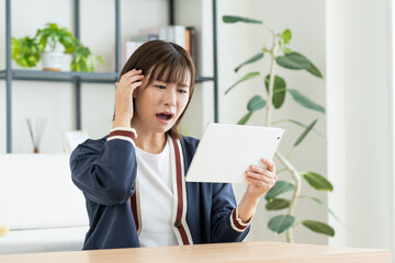 リビングでタブレットを見る若い女性