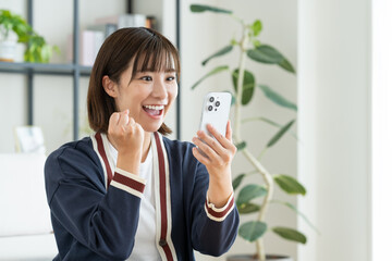 リビングでスマホを見る若い女性