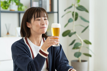 リビングでビールを飲む若い女性