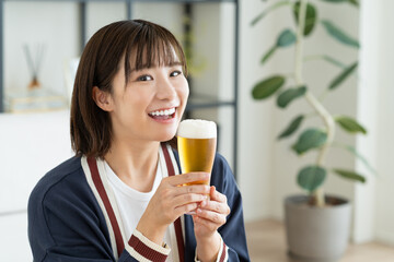 リビングでビールを飲む若い女性