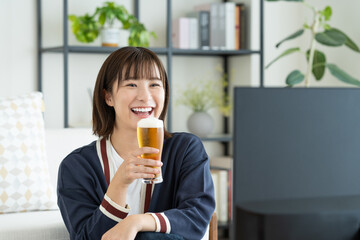ビールを飲みながらテレビを見る若い女性