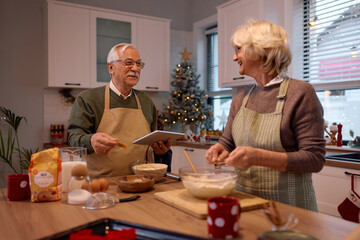 Happy senior man and his wife making Christmas cake in the kitchen.